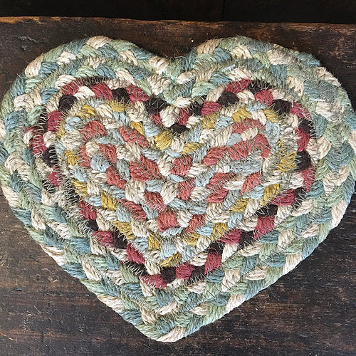 Heart shaped braided coaster in subtle greens, coral pinks, and cream from Source for the Goose, Devon.