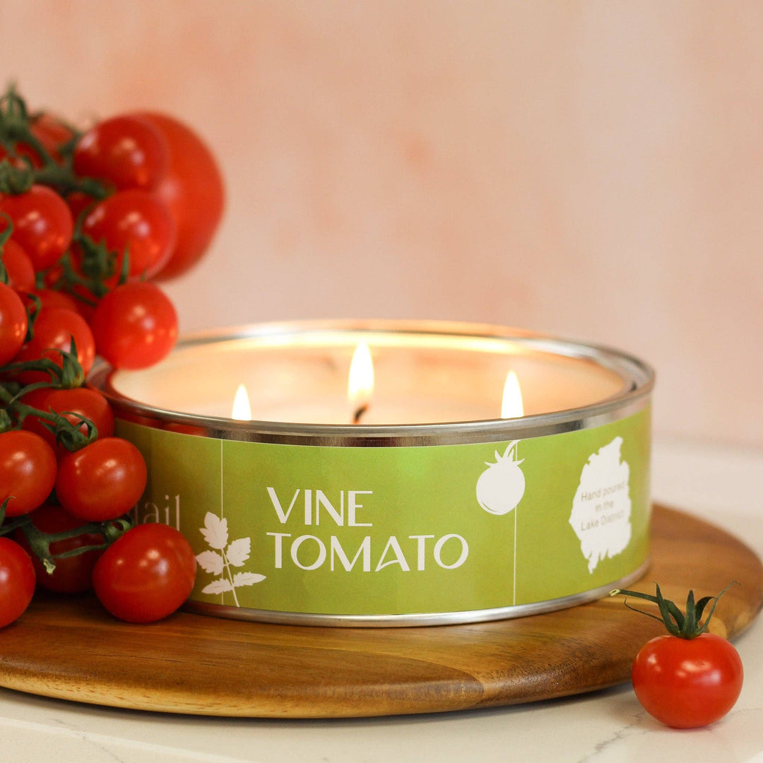 Pintail Candles Vine Tomato triple wick candle beside fresh tomatoes on a wooden board, showcasing its artisanal design.