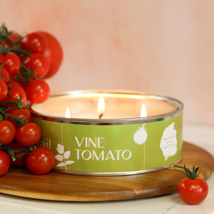 Pintail Candles Vine Tomato triple wick candle beside fresh tomatoes on a wooden board, showcasing its artisanal design.