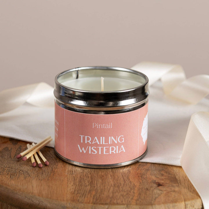 Pintail Candles- Trailing Wisteria Classic Tin on a wooden table with matches and ribbon.