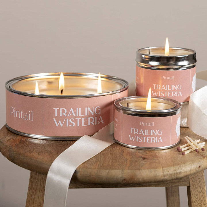 Pintail Candles- Trailing Wisteria Classic Tin in cozy setting on a wooden table with lit wicks.