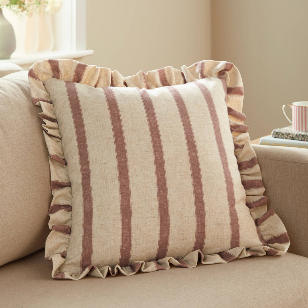 Square Striped Ruffle Cushion Clay Pink - Connie on a beige sofa, featuring a vintage striped design and frilled trim.