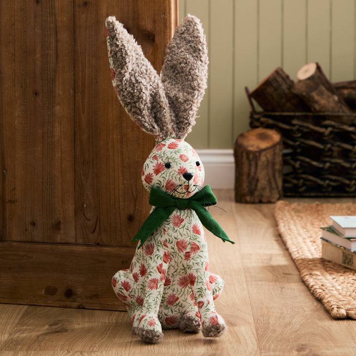 Hattie Hare Door Stop - Floral Design with handpainted floral patterns and green bow in a rustic setting.