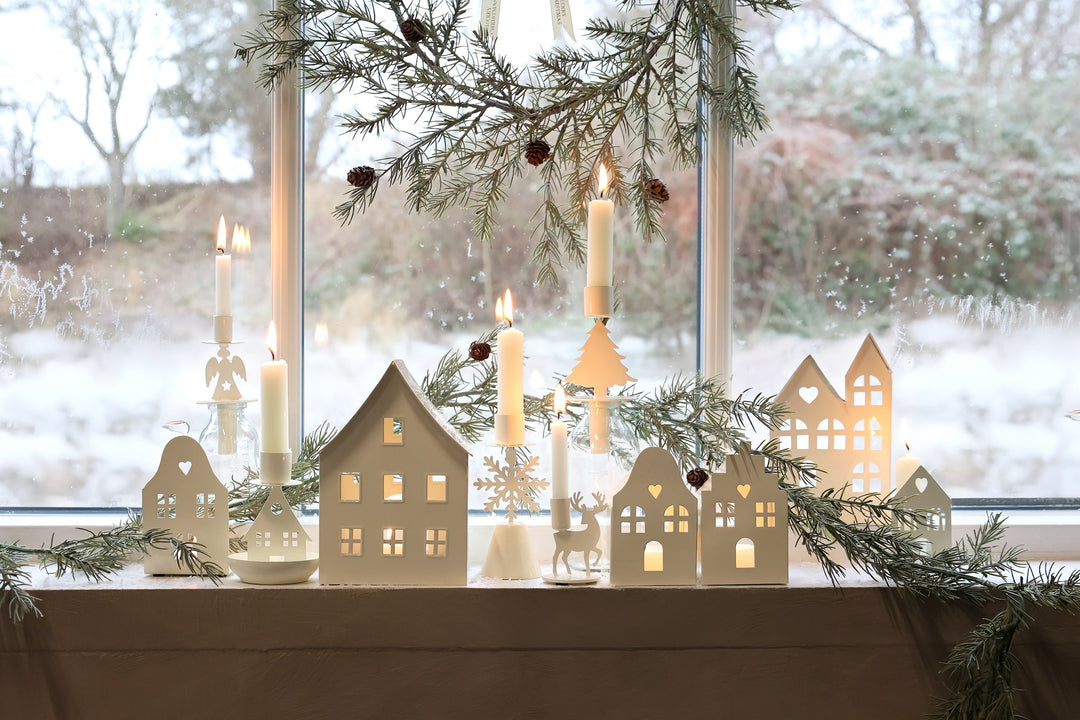 Festive winter window display with angel design candle holders and lit candles creating a cozy Christmas atmosphere.