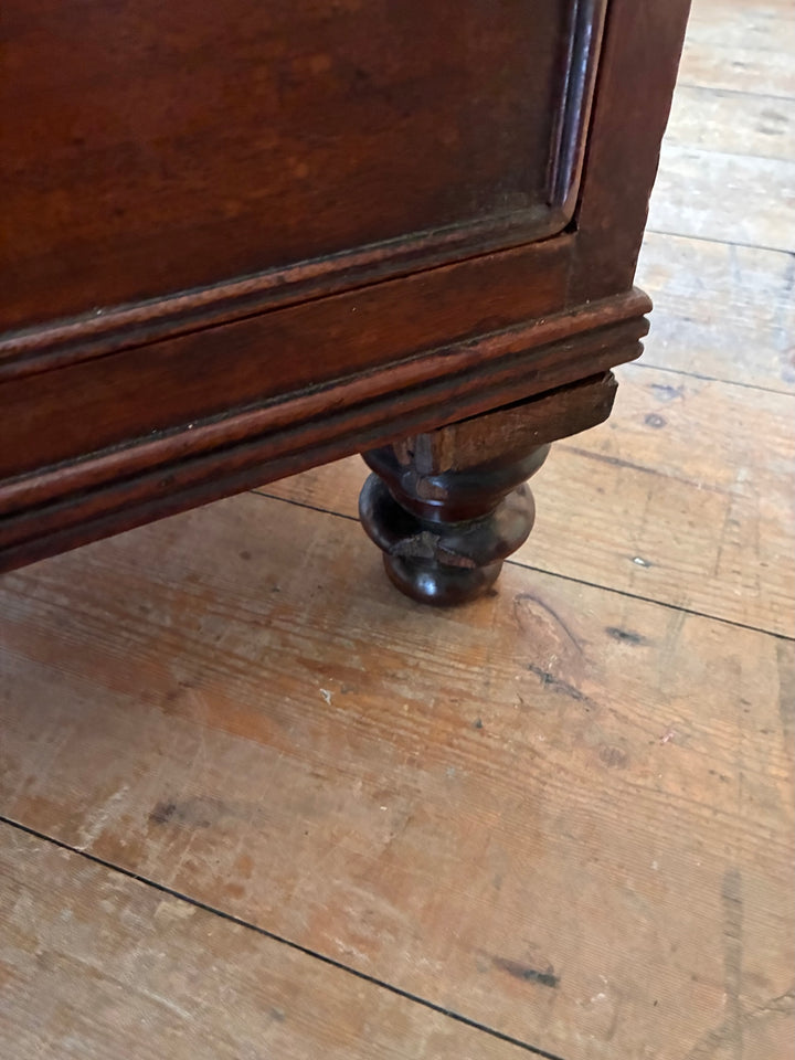 Detail of the turned foot of a Tall Antique Mahogany Chest of Drawers showcasing craftsmanship.