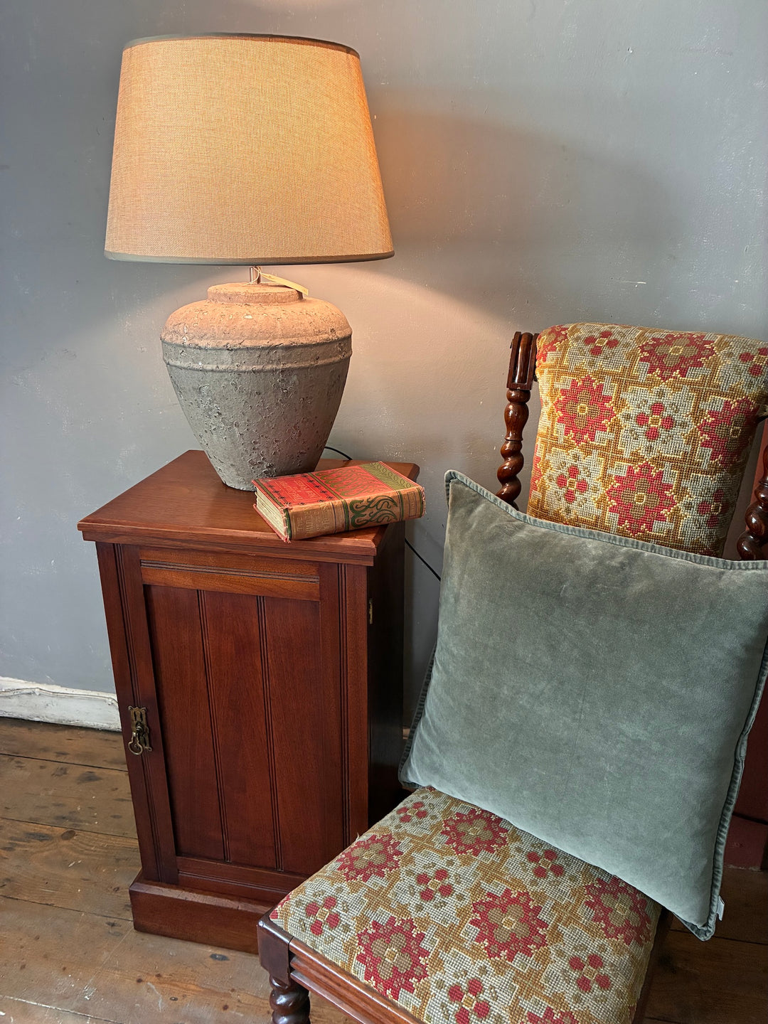 Antique Mahogany Bedside Cabinet with a lamp and decorative pillows in a cozy setting.
