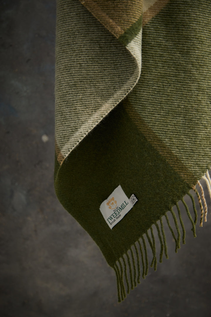 Tweedmill Block Check Olive Throw - Pure Wool hanging, showcasing its texture and label, perfect for a cosy home decor in Devon.