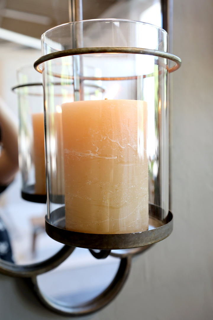 Close-up of a lit candle in a glass holder, complementing a brushed brass wall mirror by Source for the Goose Devon.