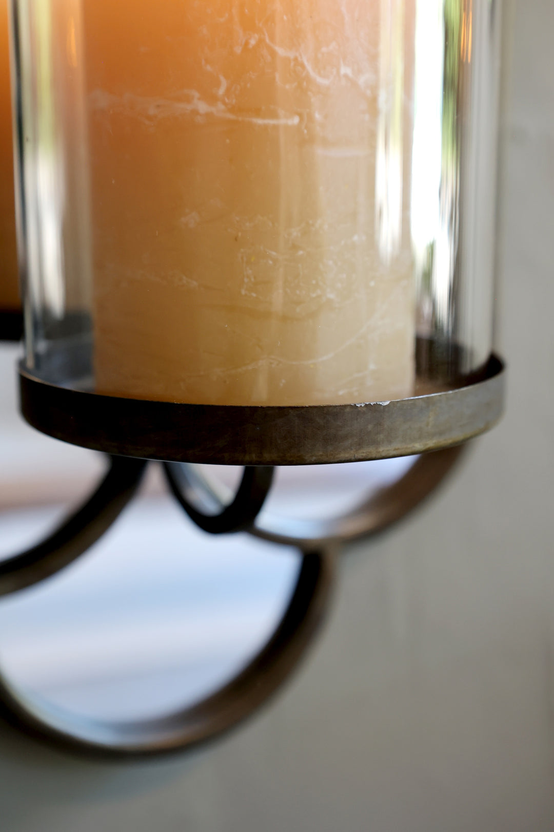 Close-up of a lit candle inside a glass holder with a brushed brass rim, enhancing vintage decor.