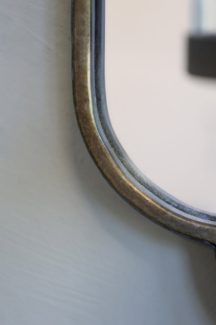 Close-up of a brushed brass wall mirror frame showcasing vintage elegance and art nouveau styling.