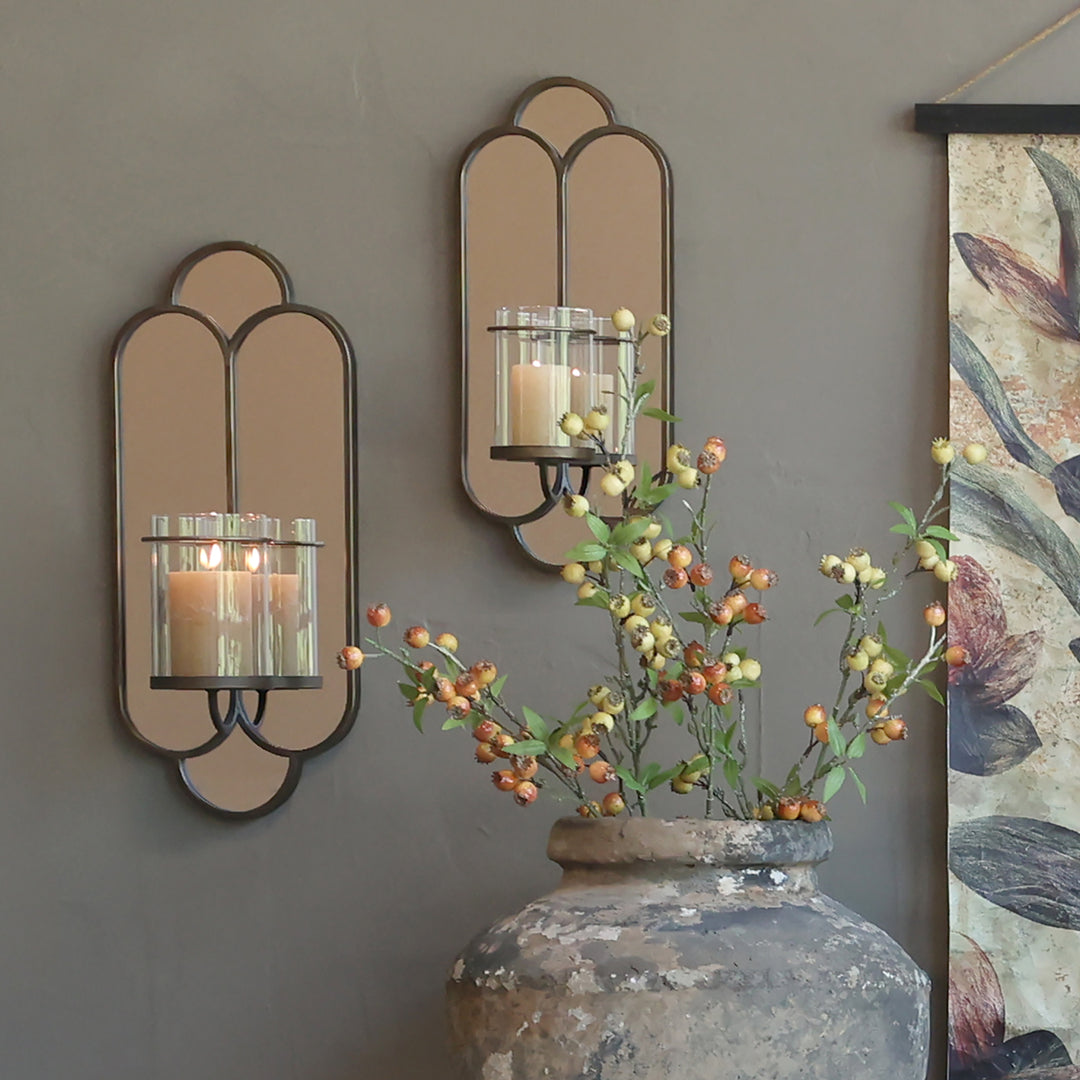 Brushed brass wall mirror with candlestick illuminating a stylish room, enhancing vintage elegance and spaciousness.