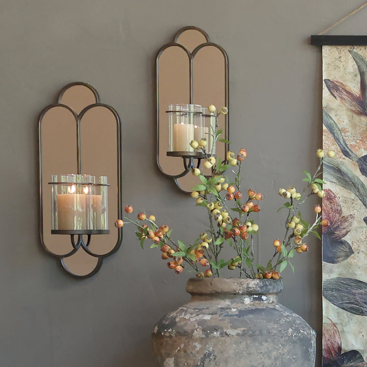 Brushed brass wall mirror with candlestick illuminating a stylish room, enhancing vintage elegance and spaciousness.