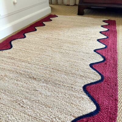 Burgundy Wave Organic Jute Braided Rug with claret wave edging and navy trim in a cozy room by Source for the Goose, Devon.