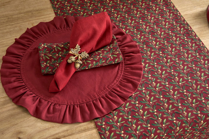 Under The Mistletoe Napkin - Set of Four arranged elegantly with a ruffled placemat and festive gold accents.