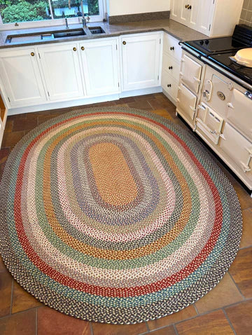 an oval jute braided rug on a kitchen floor with an aga and worktops in the background