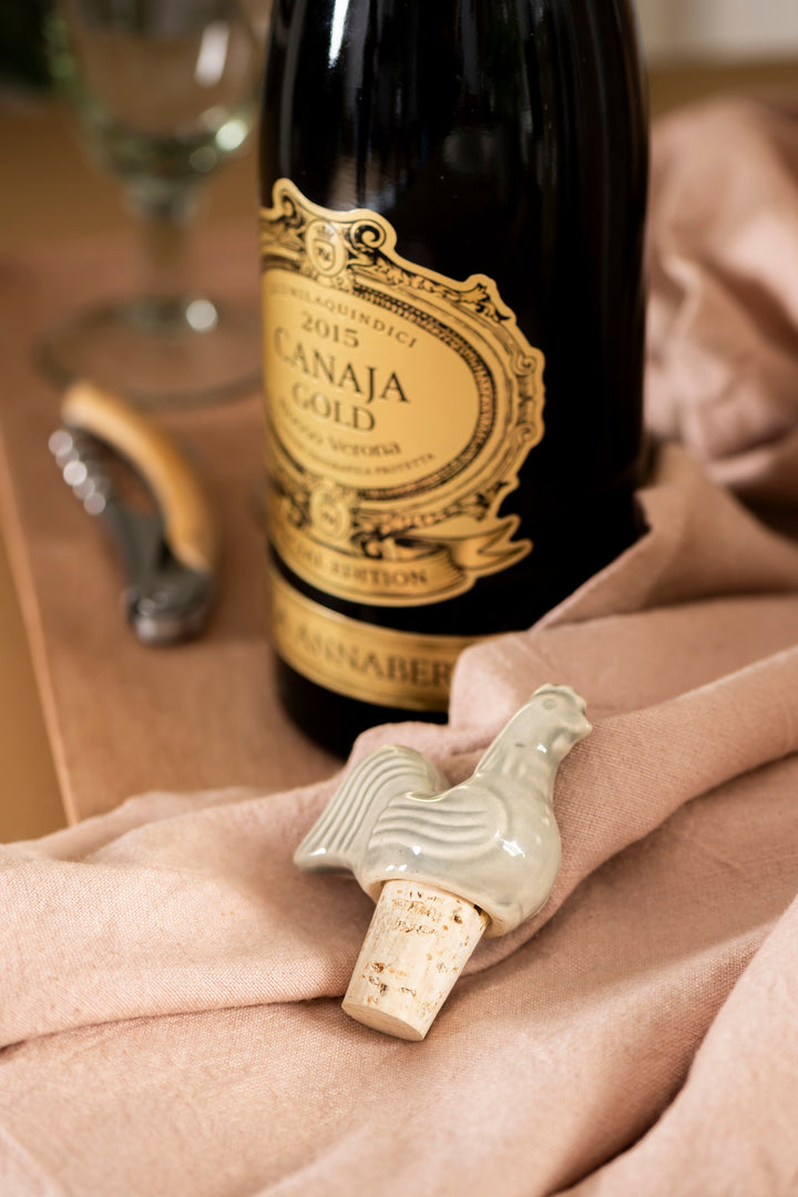 Rustic ceramic rooster bottle stopper next to a wine bottle, adding charm to any wine night. Source for the Goose, Devon.