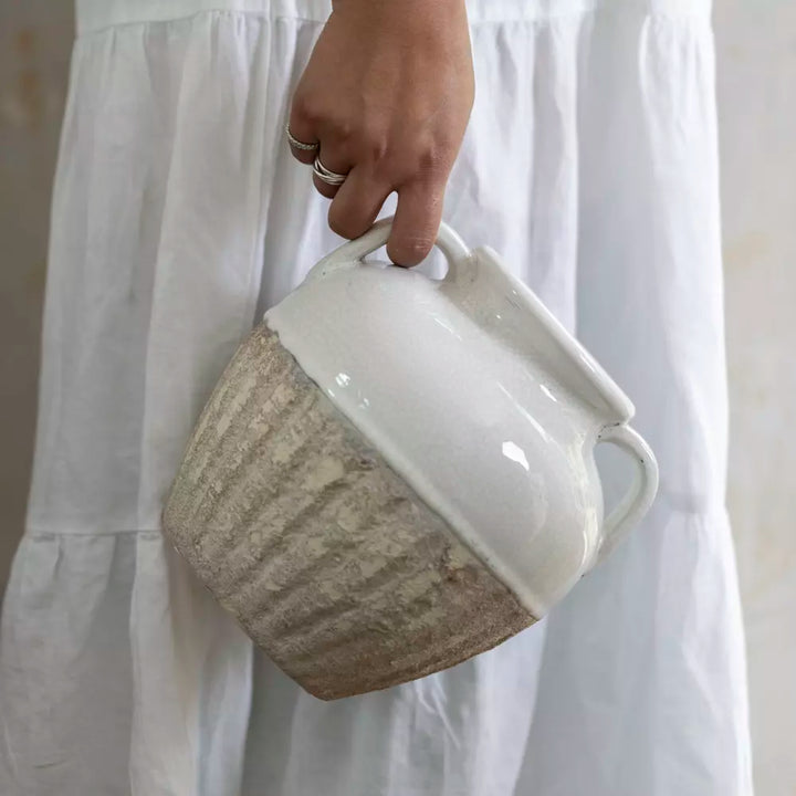 Hand holding a Small Antique White Amphora Vase with textured earthy details.