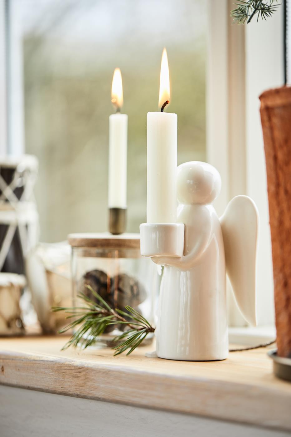white ceramic angel candle holder on a windowsill with other Christmas decor