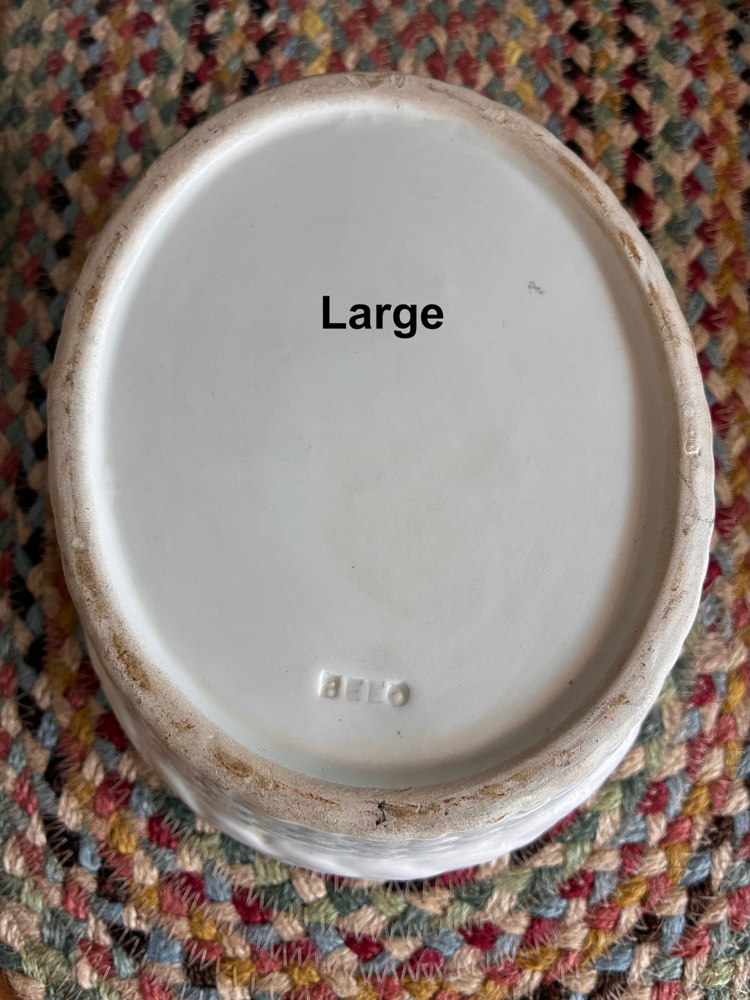 Bottom view of Chicken Egg Holder - Portugese Ceramic showing 'Large' label on a colorful woven mat.
