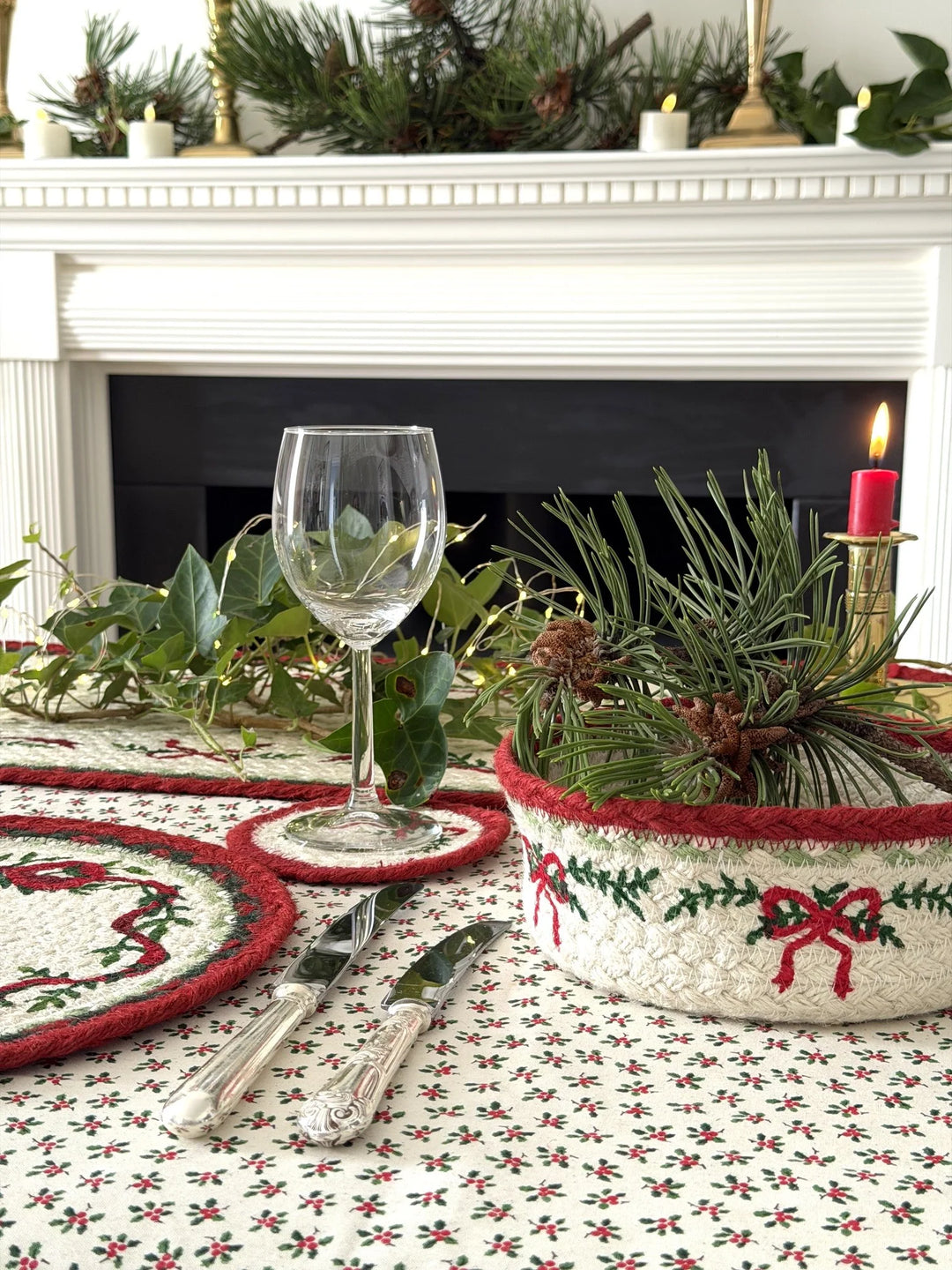 Christmas Ribbon Jute Coasters - Set of Six displayed on a festive table setting with glass, greenery, and candles.