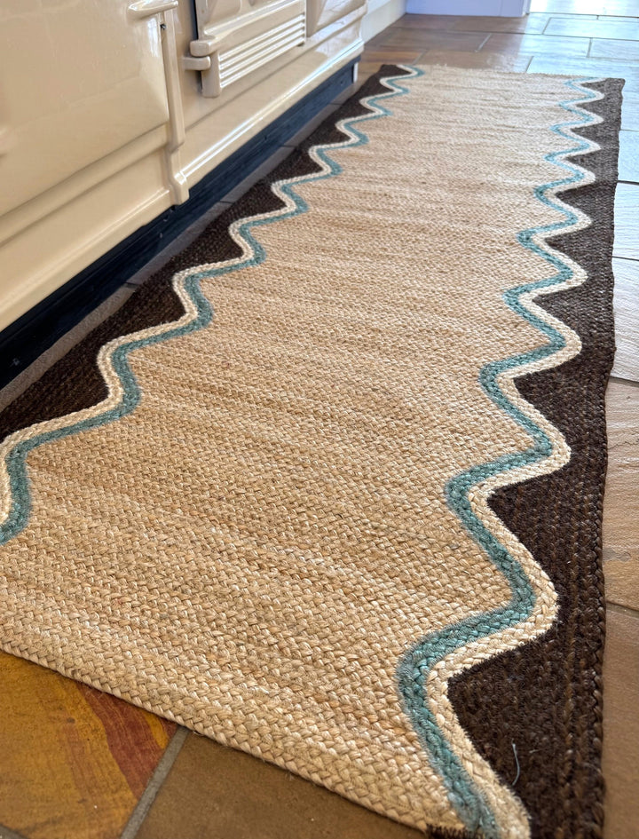 Cocoa Wave Organic Jute Braided Rug featuring a cocoa wave border and greeny blue trim.