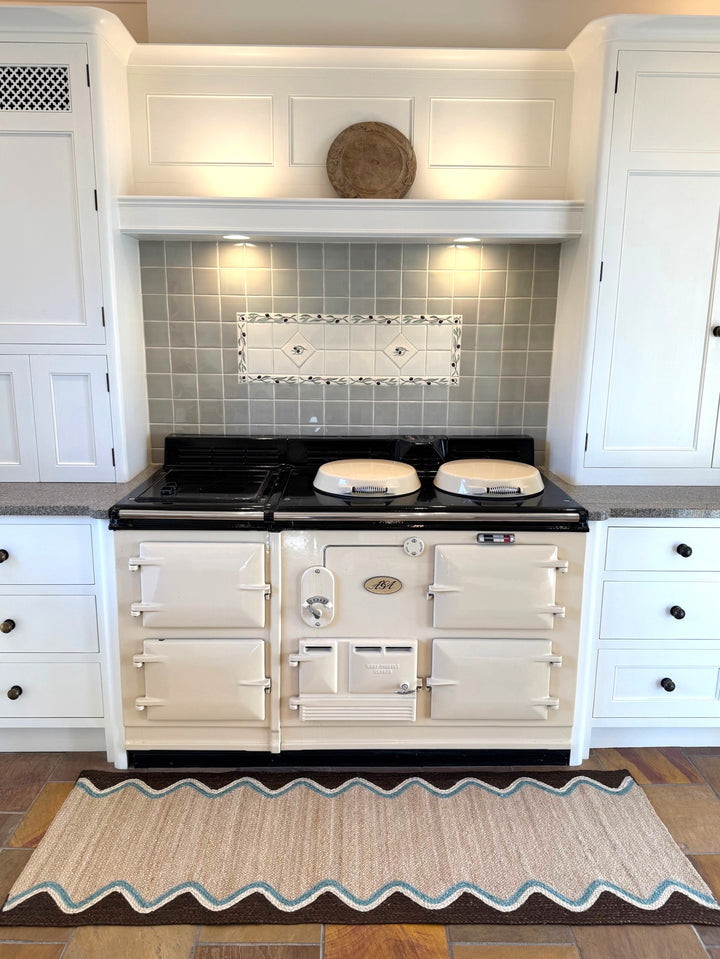 Cocoa Wave Organic Jute Braided Rug positioned in a kitchen under a classic stove for added texture and style.