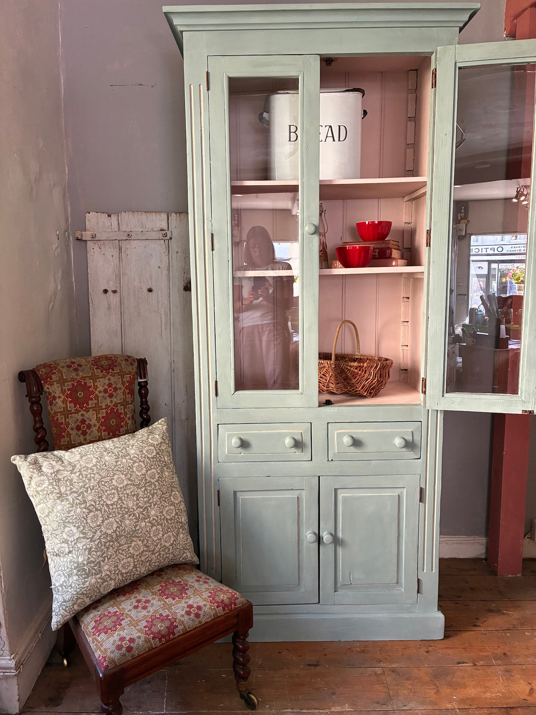 Duck Egg Blue Glazed Kitchen Dresser with glazed cupboard and pink interior displayed beside a vintage patterned chair.