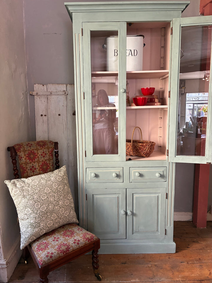 Duck Egg Blue Glazed Kitchen Dresser with glazed cupboard and pink interior displayed beside a vintage patterned chair.
