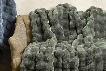 Eucalyptus Green Faux Fur Throw draped elegantly over a couch, showcasing its luxurious softness and texture.