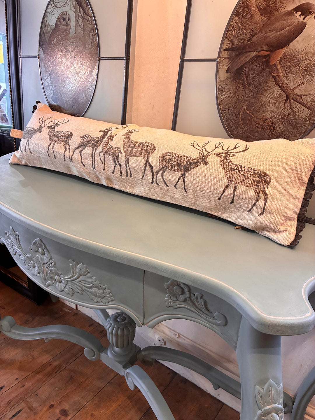 Forest Stag Draught Excluder Cushion on a rustic table, showcasing vintage style and stag silhouettes.