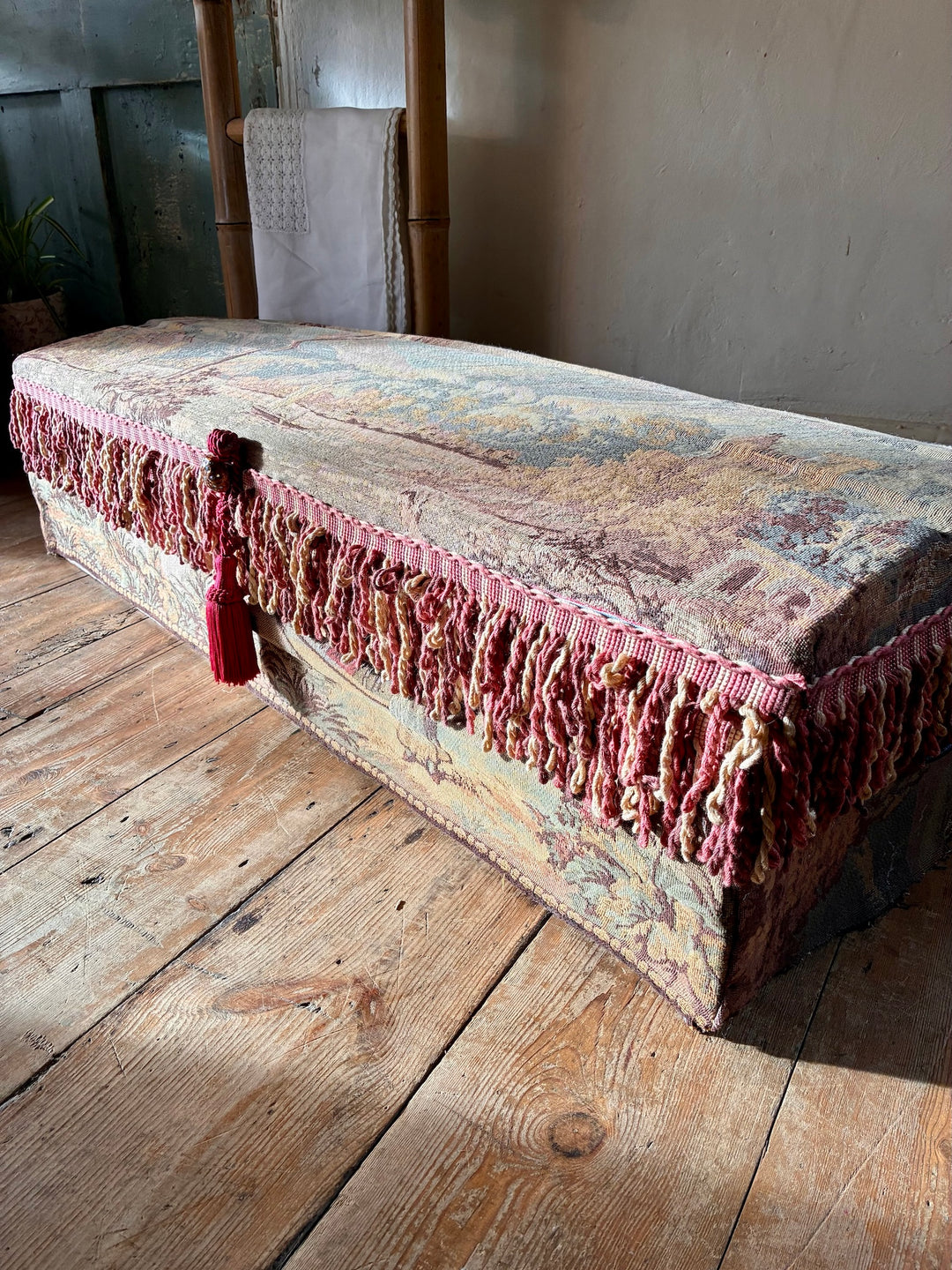 French Upholstered Storage Trunk - Bridal Trunk with pink tassels and vintage tapestry fabric on a wooden floor.