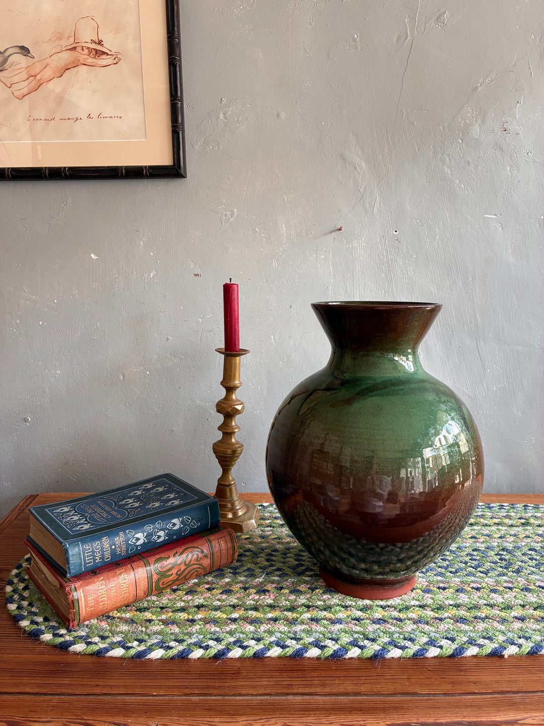 Glazed studio pottery vase by Vresh Kanikanian in green tones, displayed with books and a candle, Source for the Goose, Devon.