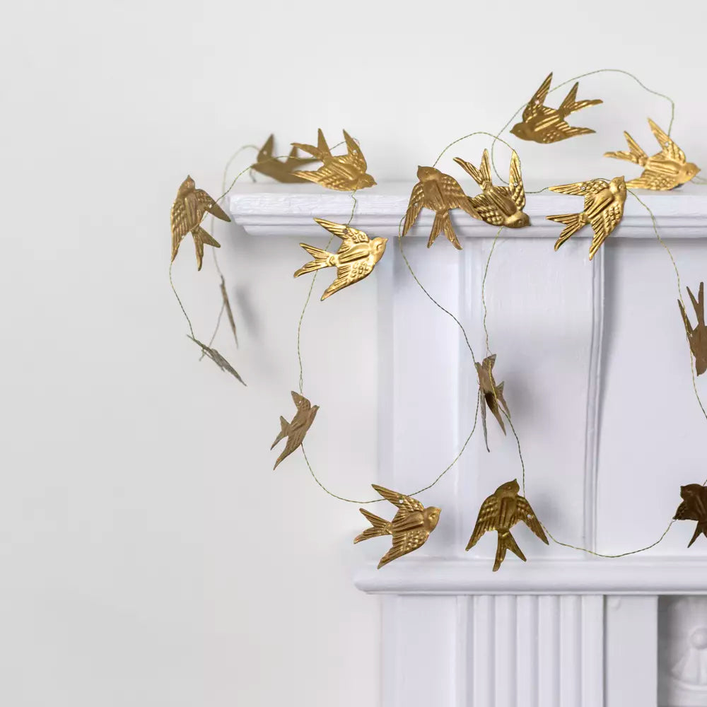 Gold Bird Garland on Wire featuring golden swifts draped elegantly on a white mantel, perfect for festive decor.