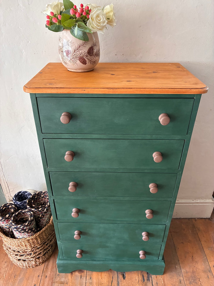 Tall Dark Green Chest of Drawers with hand painted finish and rustic country charm, topped with a vase of flowers.