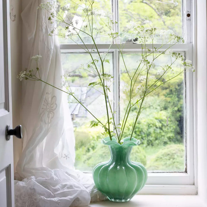 Green Glass Vase with Frill Rim - Bethany filled with delicate flowers on a windowsill, enhancing room decor.