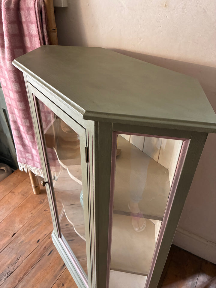 Soft Green Corner Display Cabinet from Source for the Goose, showcasing glass doors and pink-edged trims.