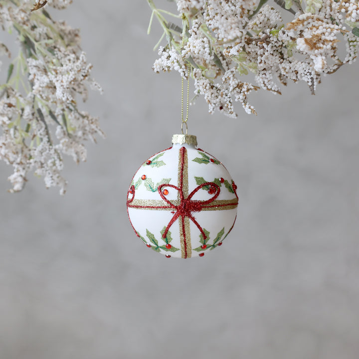 Hand-painted glass Christmas bauble with holly and red ribbon, perfect for festive decor from Source for the Goose, Devon.