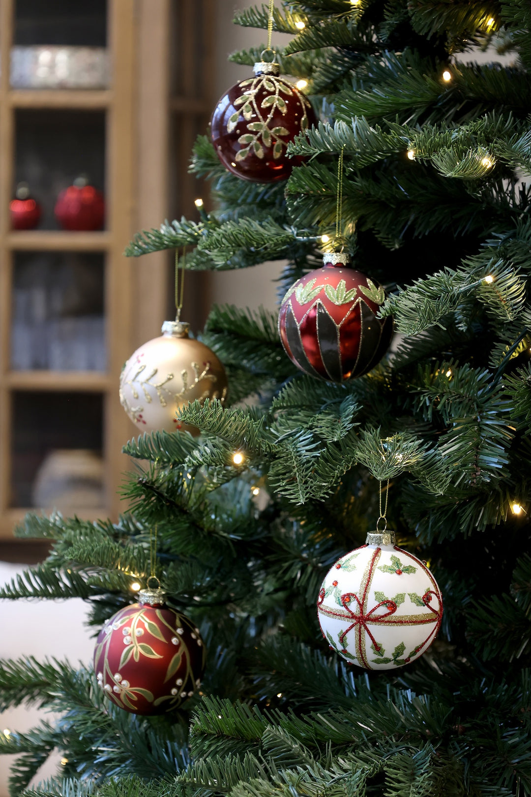 Decorative glass Christmas baubles in rich red and gold, hanging on a festive tree, showcasing holiday charm.