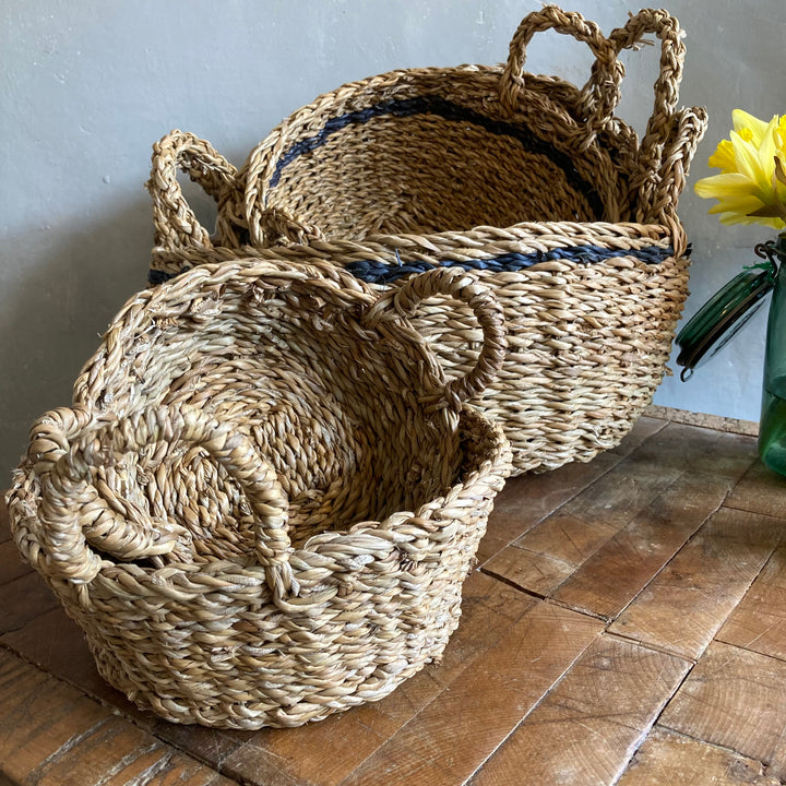 Round Jute Basket with Handles in front of Hogla Basket at Source for the Goose 