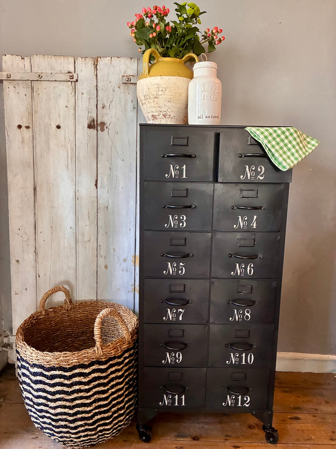 Industrial Style Metal Cabinet with Drawers featuring numbered drawers and lockable wheels, styled with decorative items.