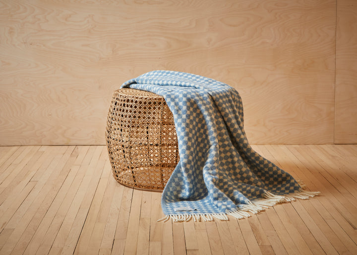 wool throw with blue jacquard design draped over a stool
