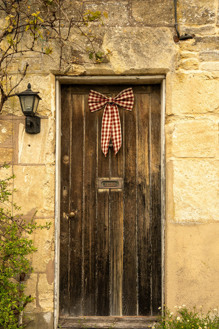 Large Gingham Bow - Two Colours adorns a rustic door, enhancing cottage core aesthetics with vintage style charm.