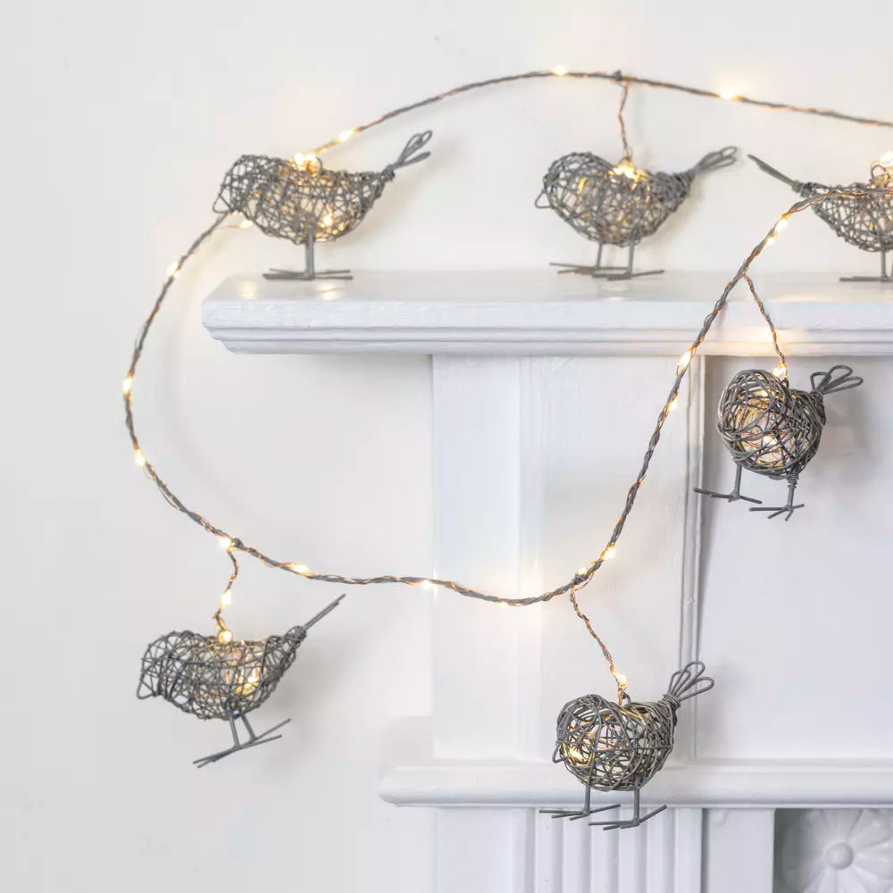 Light Up Wire Bird Garland - Antique Grey with LED lights on mantel, featuring intricately crafted wire birds.