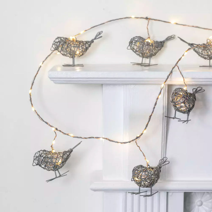 Light Up Wire Bird Garland - Antique Grey with LED lights on mantel, featuring intricately crafted wire birds.