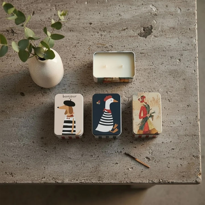 Lemoncello Scented Candle in a Tin - Parisian Duck displayed on a table with stylish decorative tins and a small vase.