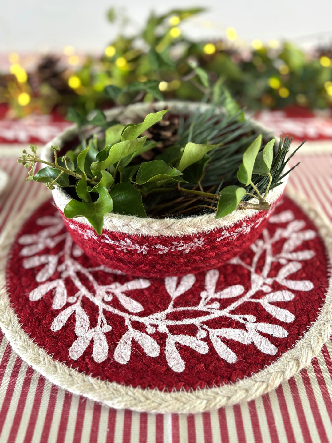 Christmas Red Berry Jute Mini Basket filled with greenery on a festive striped table setting.