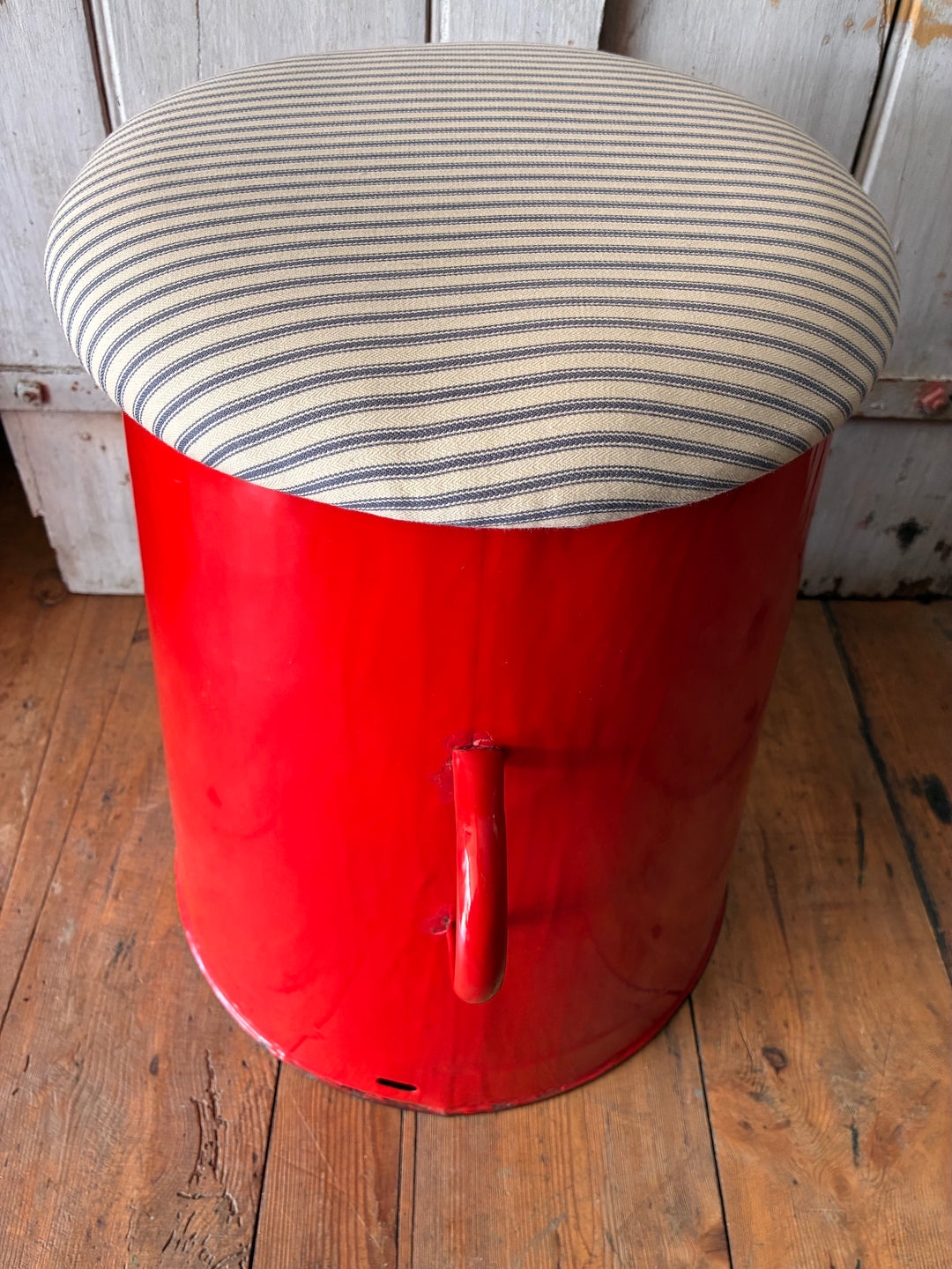 Quirky red enamel stool with blue stripe ticking lid, perfect for storage and stylish hallway decor.