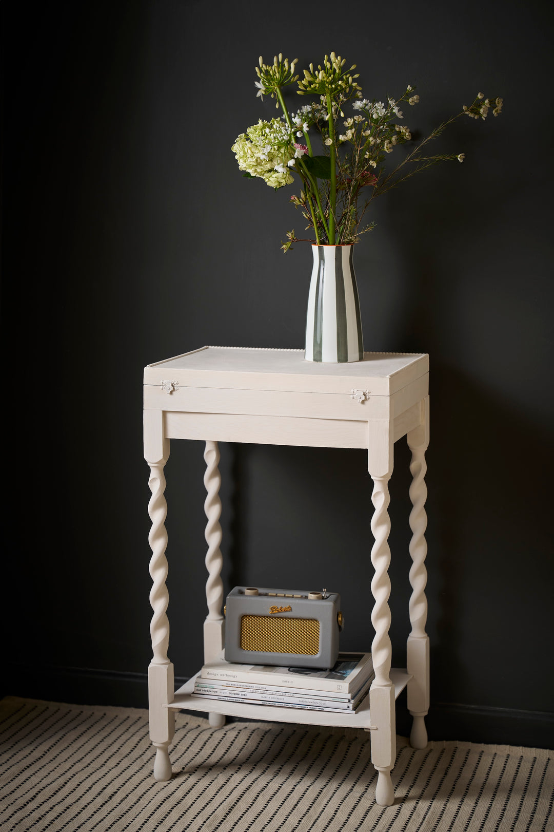 Stylish white side table with twisted legs, featuring a vase of flowers and retro radio, perfect for any interior decor.