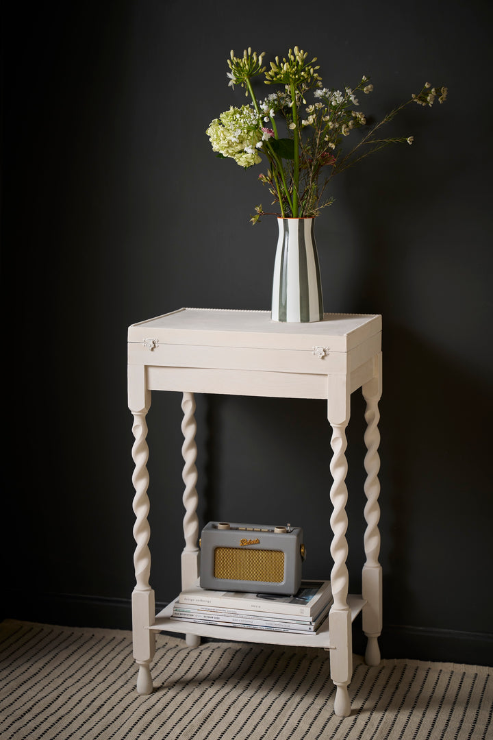 Stylish white side table with twisted legs, featuring a vase of flowers and retro radio, perfect for any interior decor.
