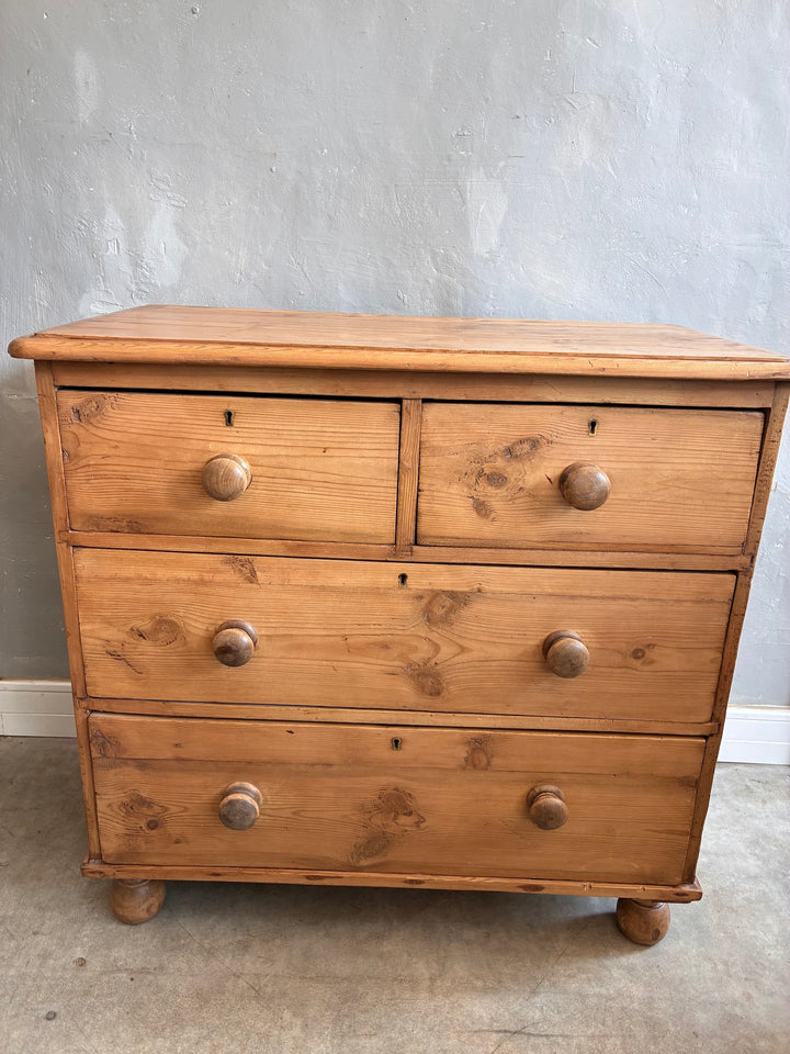 Rustic antique pine chest of drawers with two over two drawers, original knobs, and turned feet from Source for the Goose, Devon.
